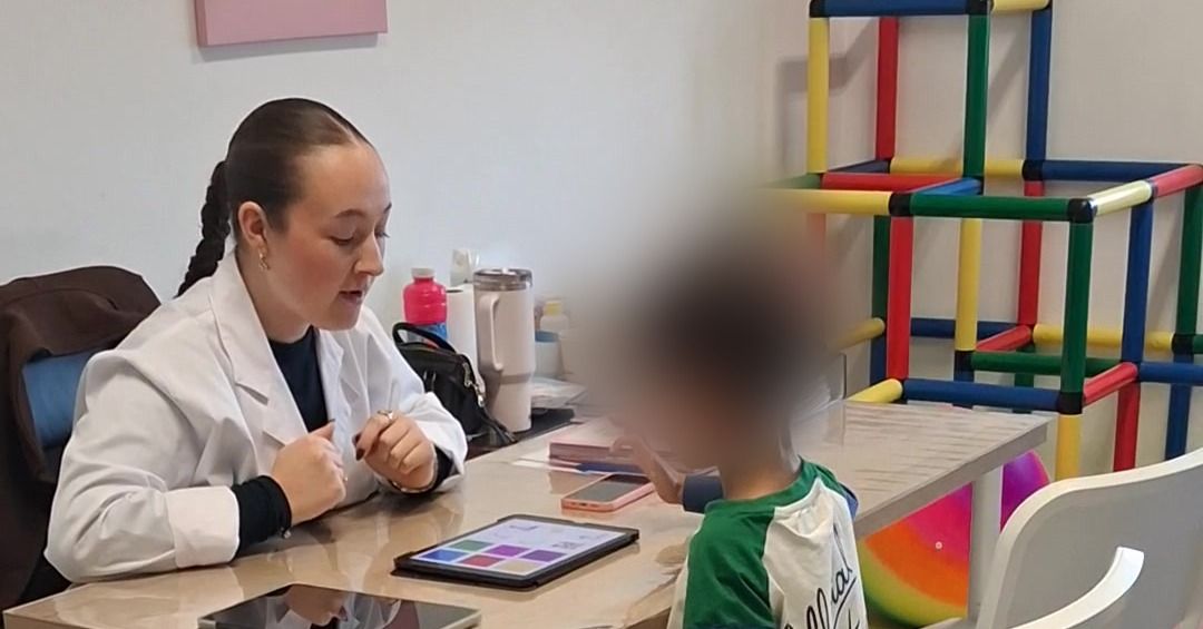 Sala de Terapia da Fala: a Terapeuta Inês Castro e uma criança sentadas à mesa durante uma sessão